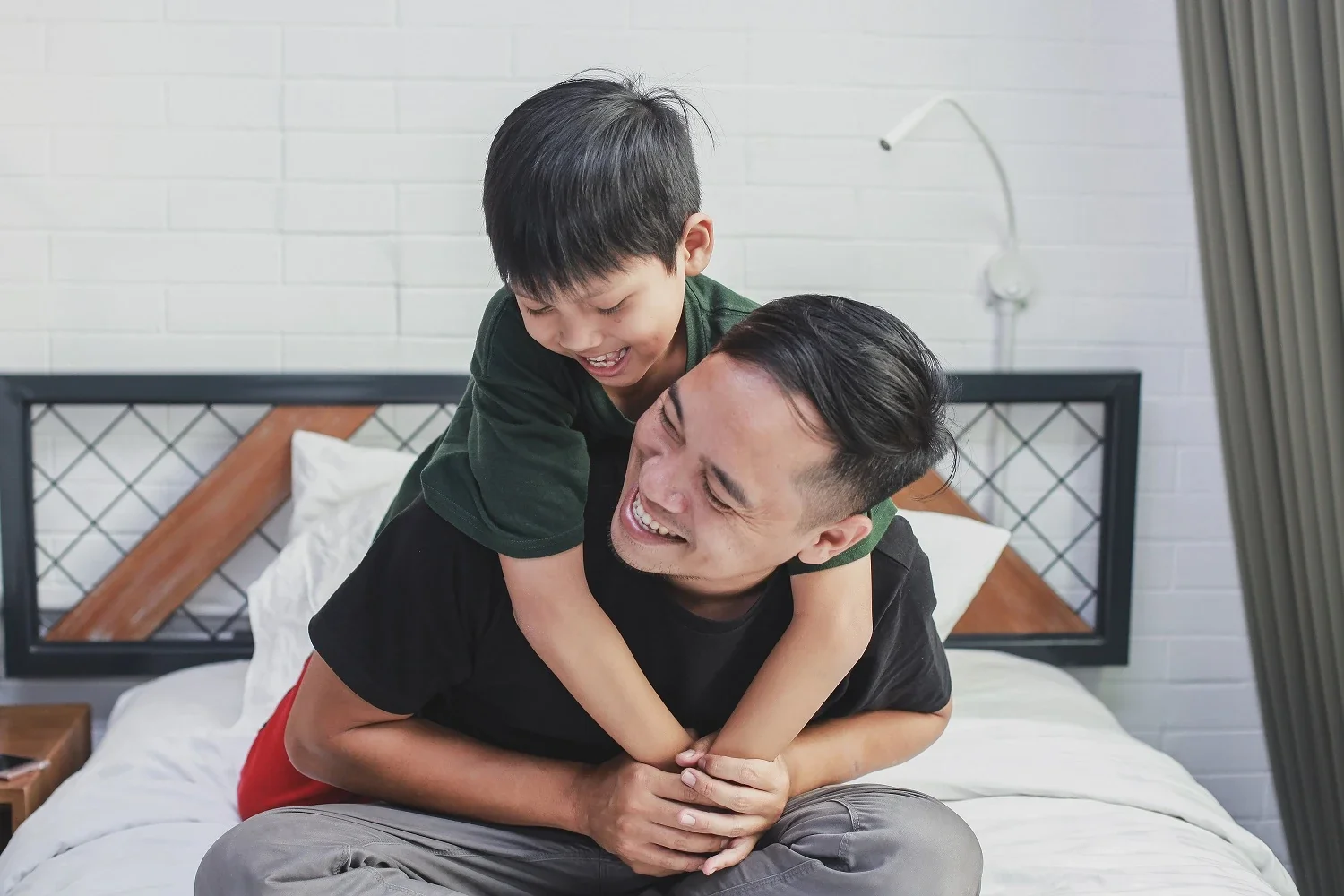 A smiling father carrying his son on his back at home